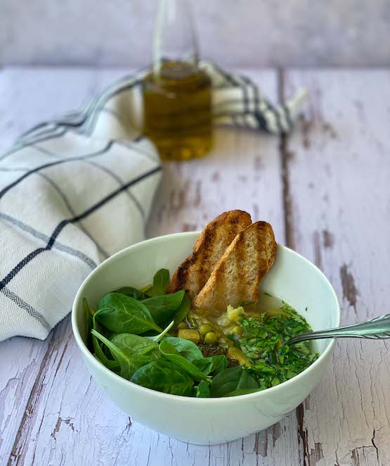 Green Detox Spring Soup in a bowl with bread and olive oil in the back
