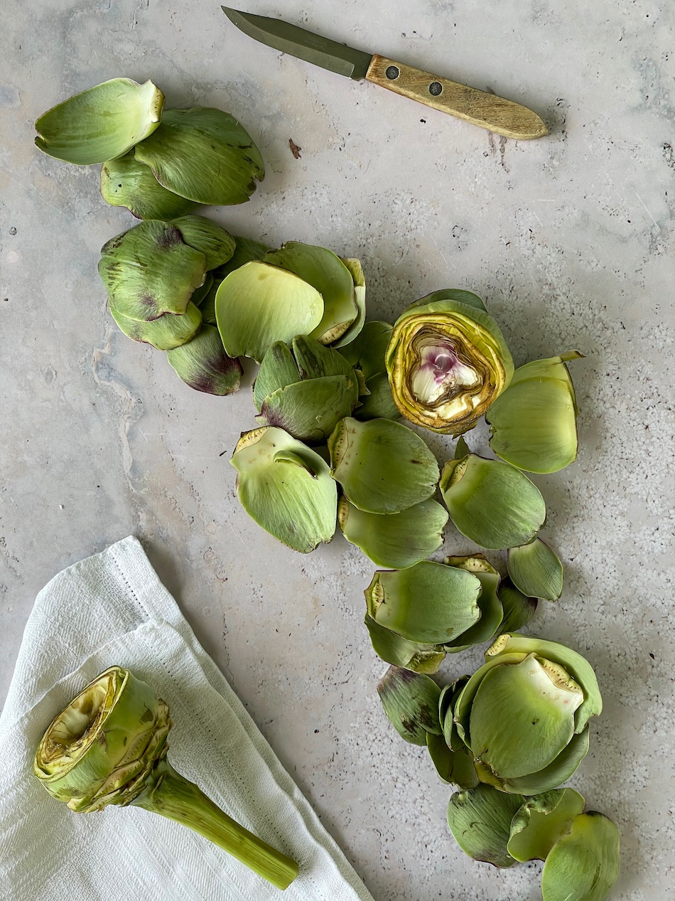 Artichokes on a marble counter with a white towel.