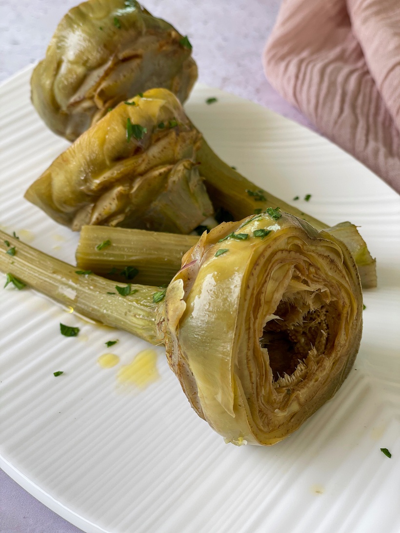 Sauteed-Artichokes on a white plate with beige napkins in background