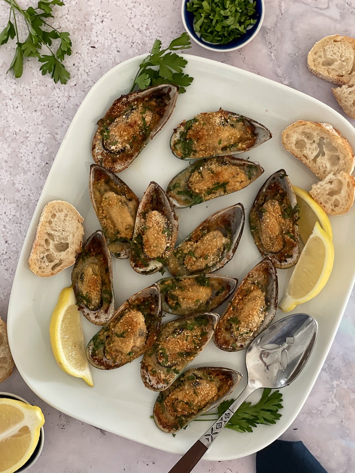 Baked Mussels on white plate with lemon and baguette