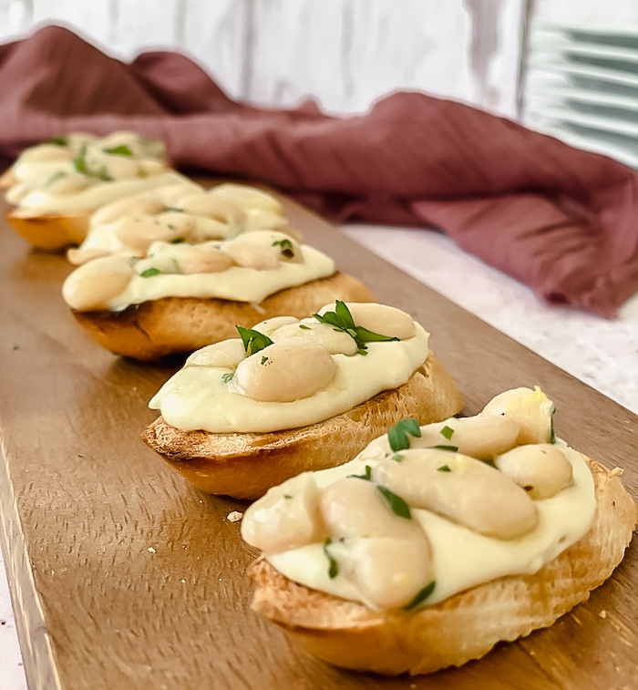 White bean crostini appetizer on board of wood