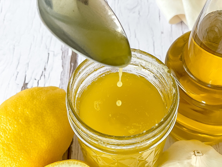 Spoon in a glass jar full of lemon garlic vinaigrette dressing.