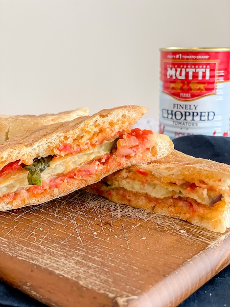 Caramelized Tomato Panini over a board with a jar of Mutti chopped tomatoes in the back