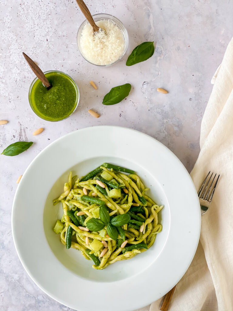 trofie al pesto with a small jar of pesto and Parmesan
