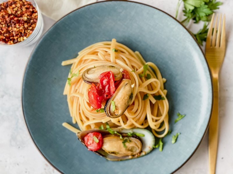 Pasta with mussels and tomatoes on a blue plate