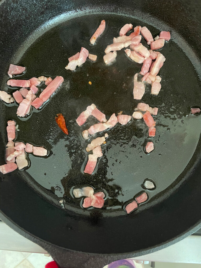 Adding red pepper flakes to pork jowl, essential in Pasta all'Amatriciana recipe