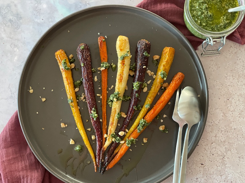 roasted carrot with a jar of pesto