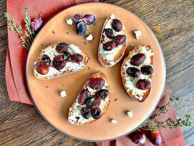Crostini with grapes and goat cheese over a plate