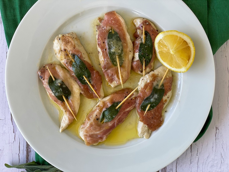 Chicken tenders with ham and sage on a white plate