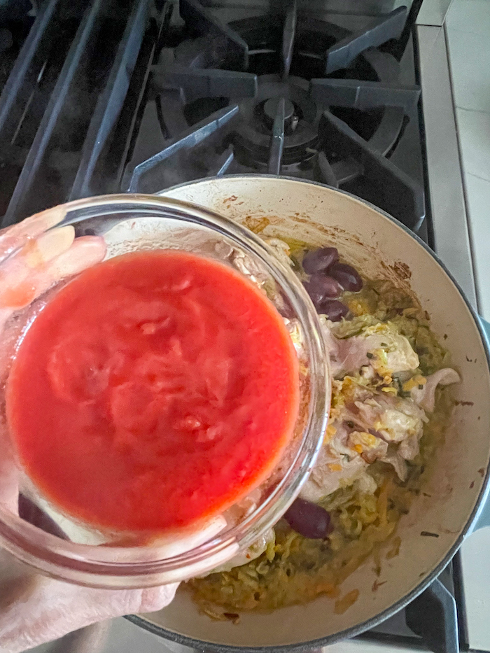 Adding Adding tomato sauce to the chicken cacciatore