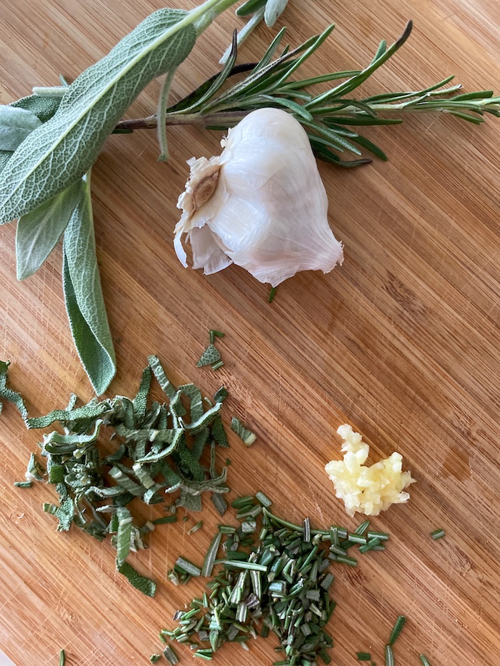 Fresh herbs and garlic over a chopping board