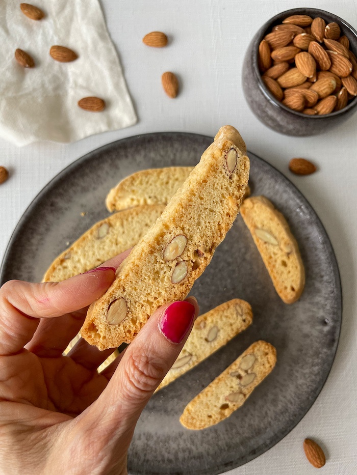 Classic Almond Biscotti in hand over a grey plate