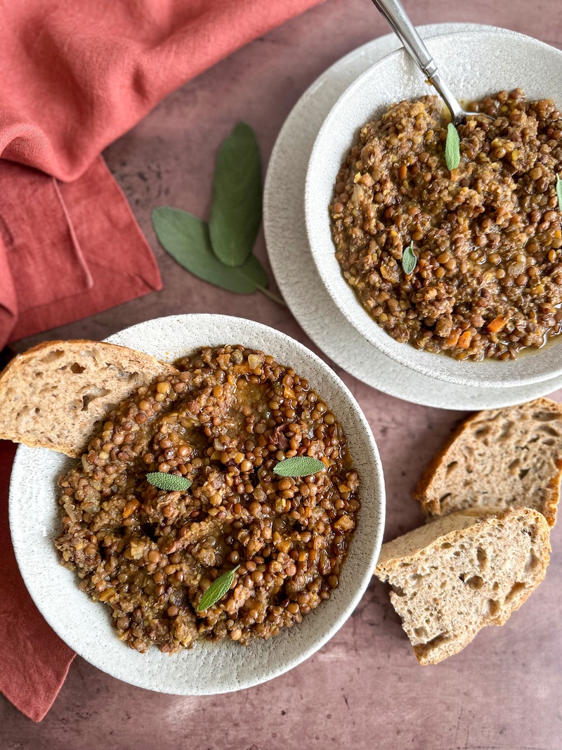 2 bowls of Italian Lentil Soup with prosciutto with some bread slices.