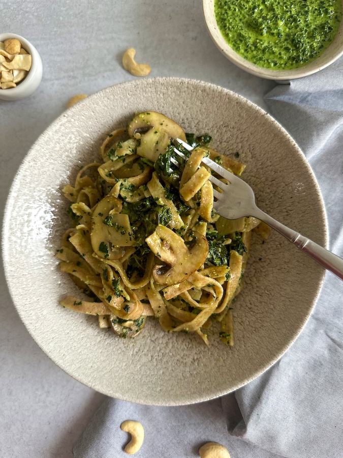 Spelt tagliatelle pasta on white bowl with blue napkins