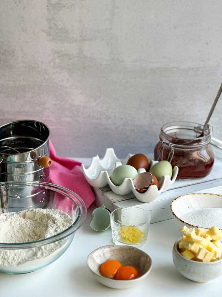Crostata di marmellata ingredients with egg tray and jam jar in the back