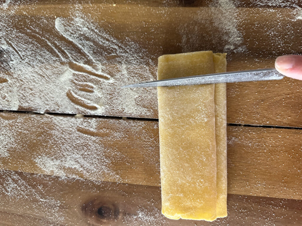cutting pasta dough in pappardelle with a sharp knife