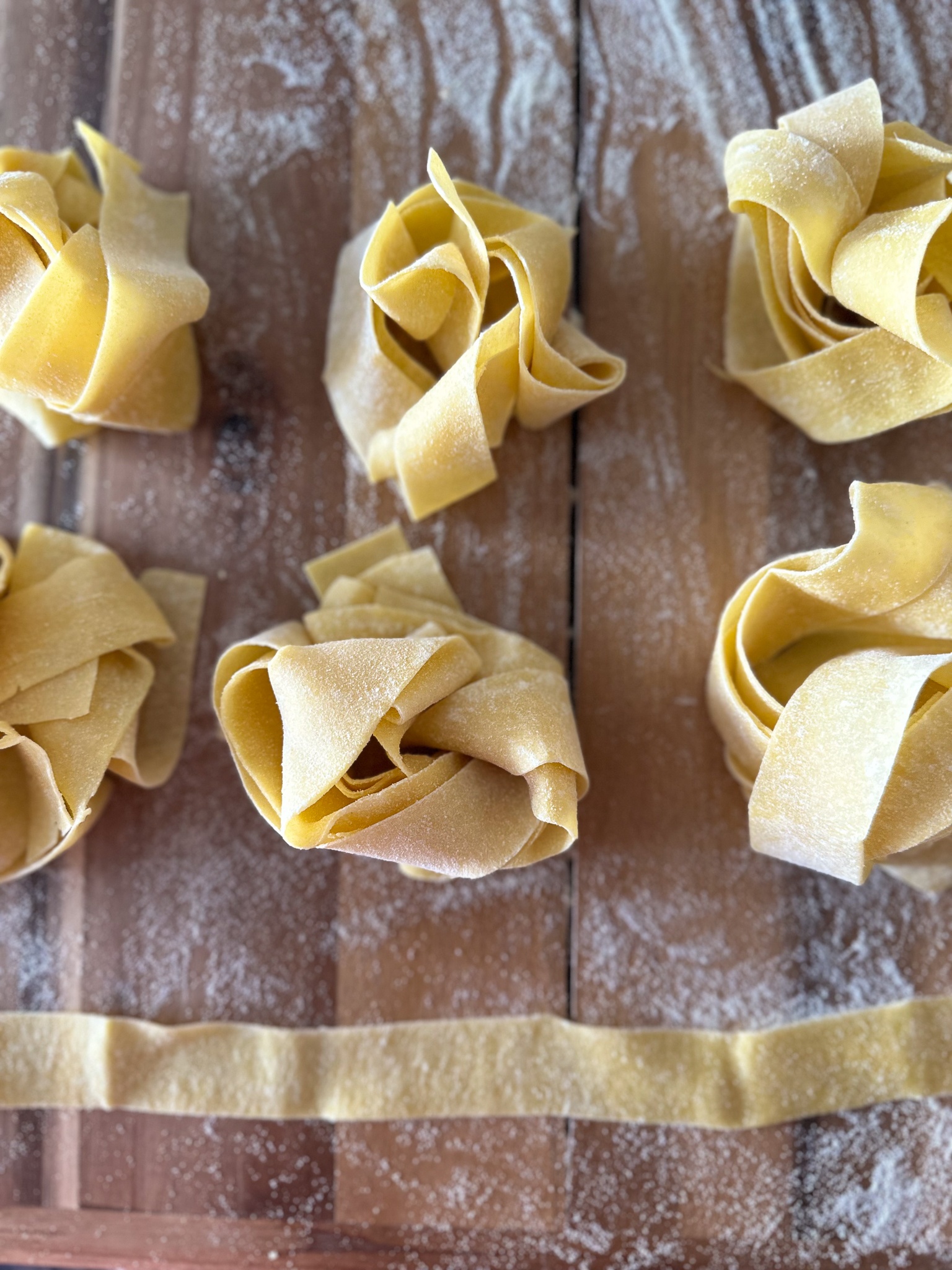 Homemade Pappardelle Pasta nests on a wooden surface