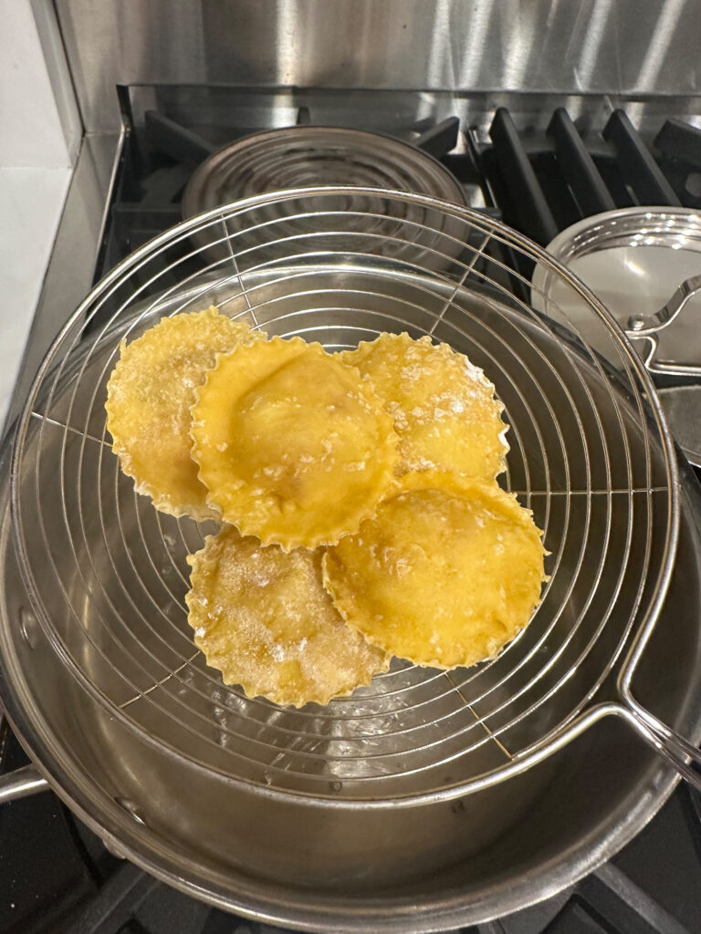 Inserting Sea Bass Ravioli in water with slotted spoon