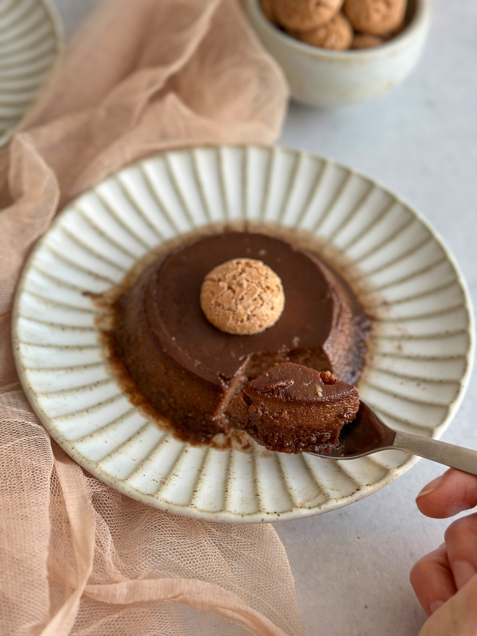 Bonet pudding in a platee with a spoon and hand