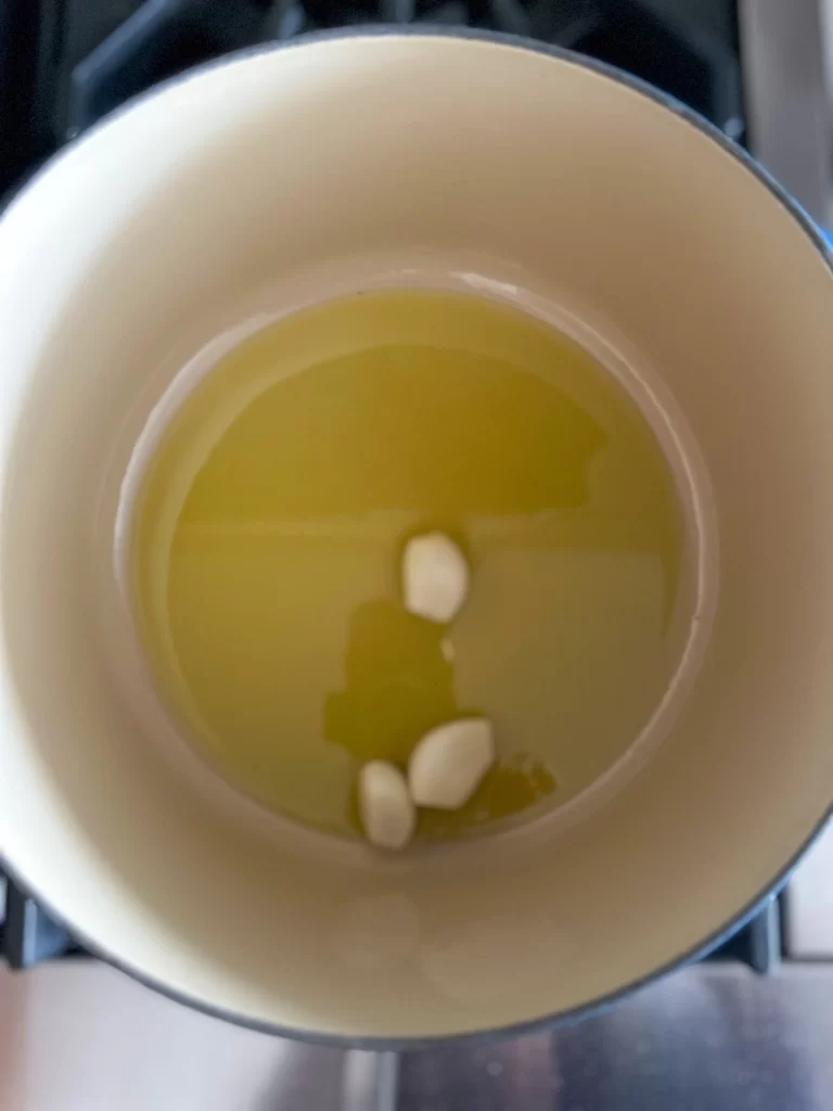 Garlic cloves added to a Dutch pot with oil.