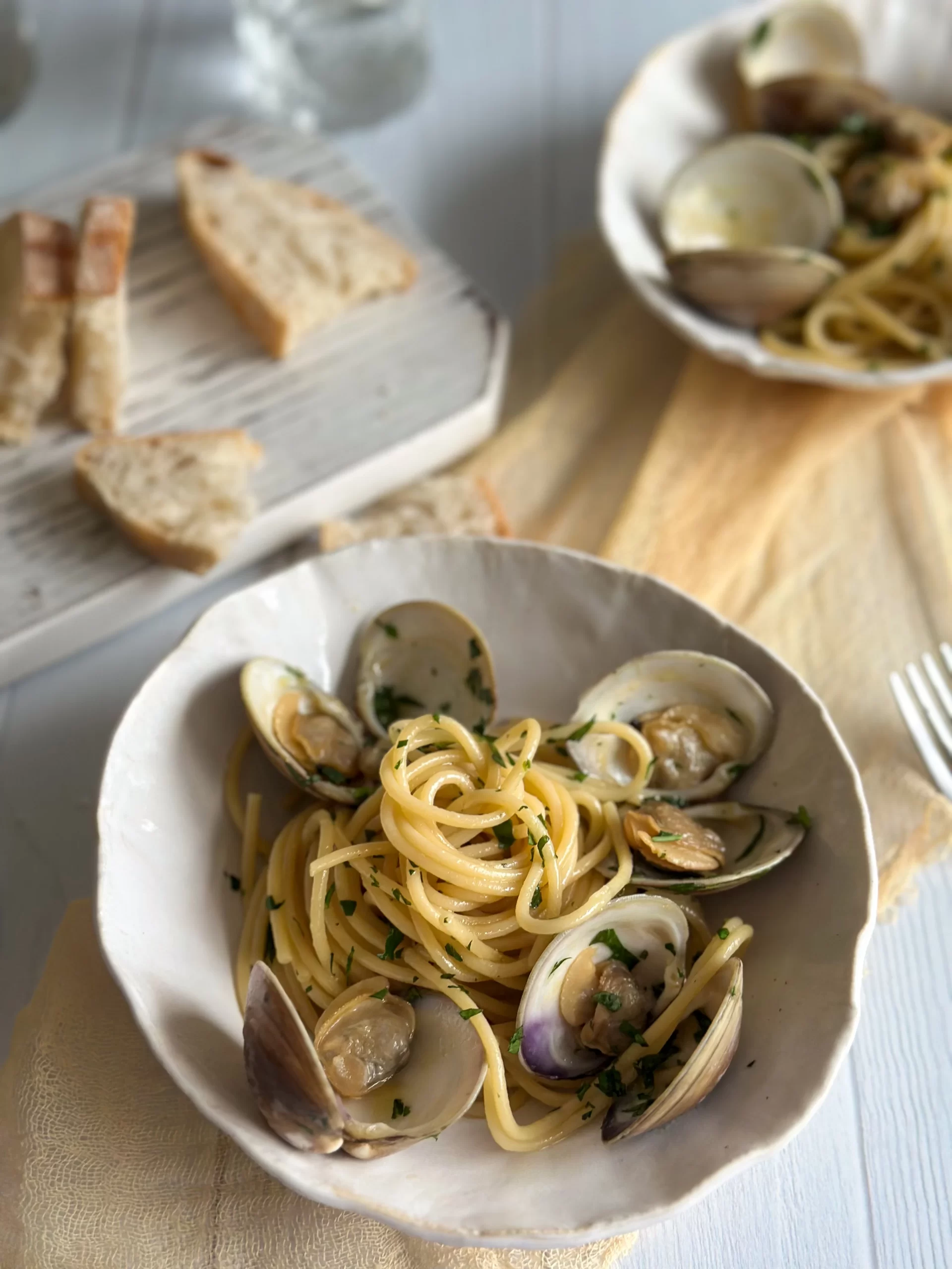 clams spaghetti in a playte woth bread slices in background