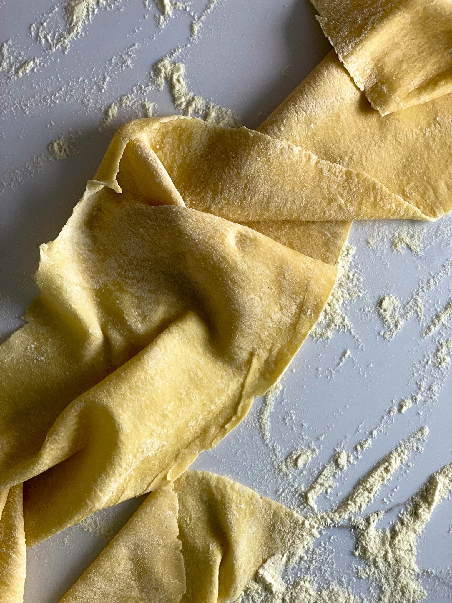 Homemade pasta sheet rolled out on a marble surface