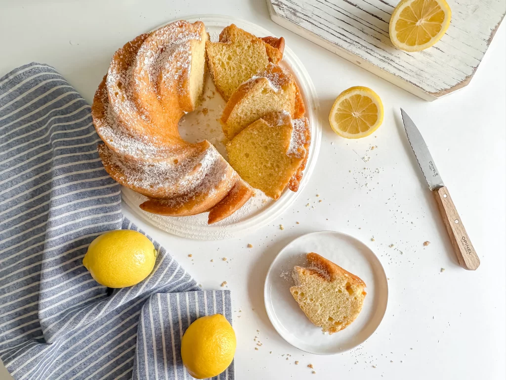 sliced lemon olive oil cake on a table with a plate and a slice in it