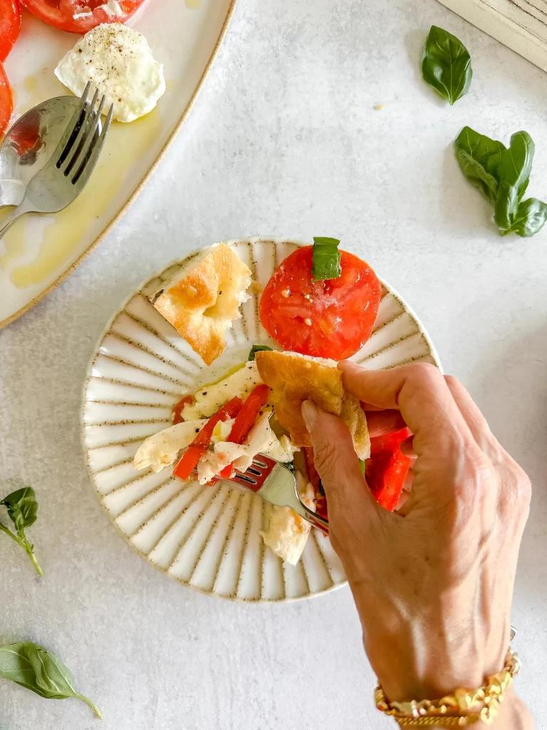 Dunking focaccia to absorb the pool of tomato liquid, cheese whey and olive oil.