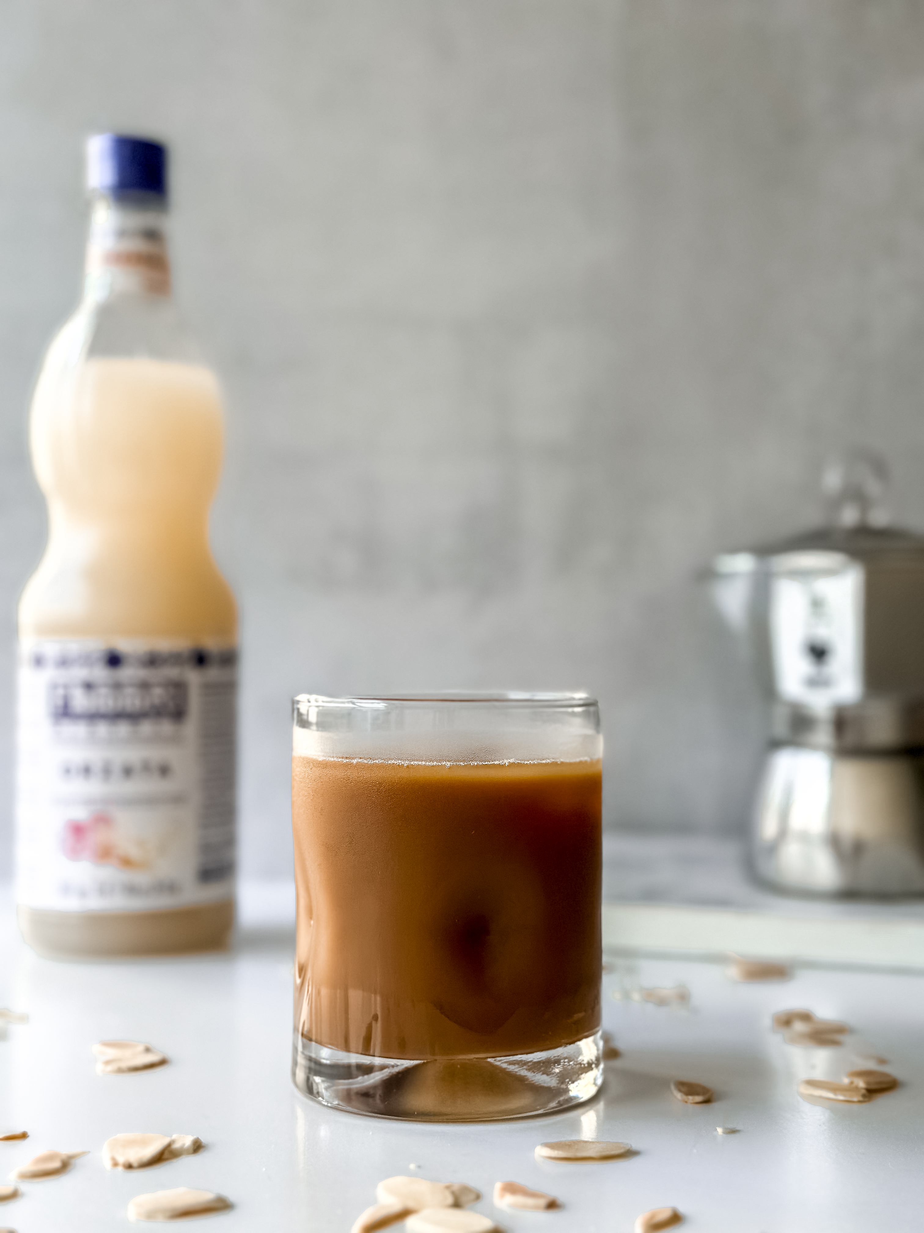 Orgeat Syrup Iced Cofee (Caffe'Freddo con Orzata) with a mock and orzata bottle in background