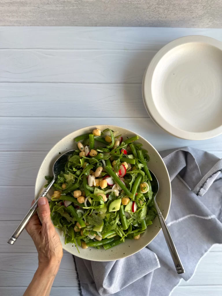 Salad sering bowls hold by a hand with plates on the sides.