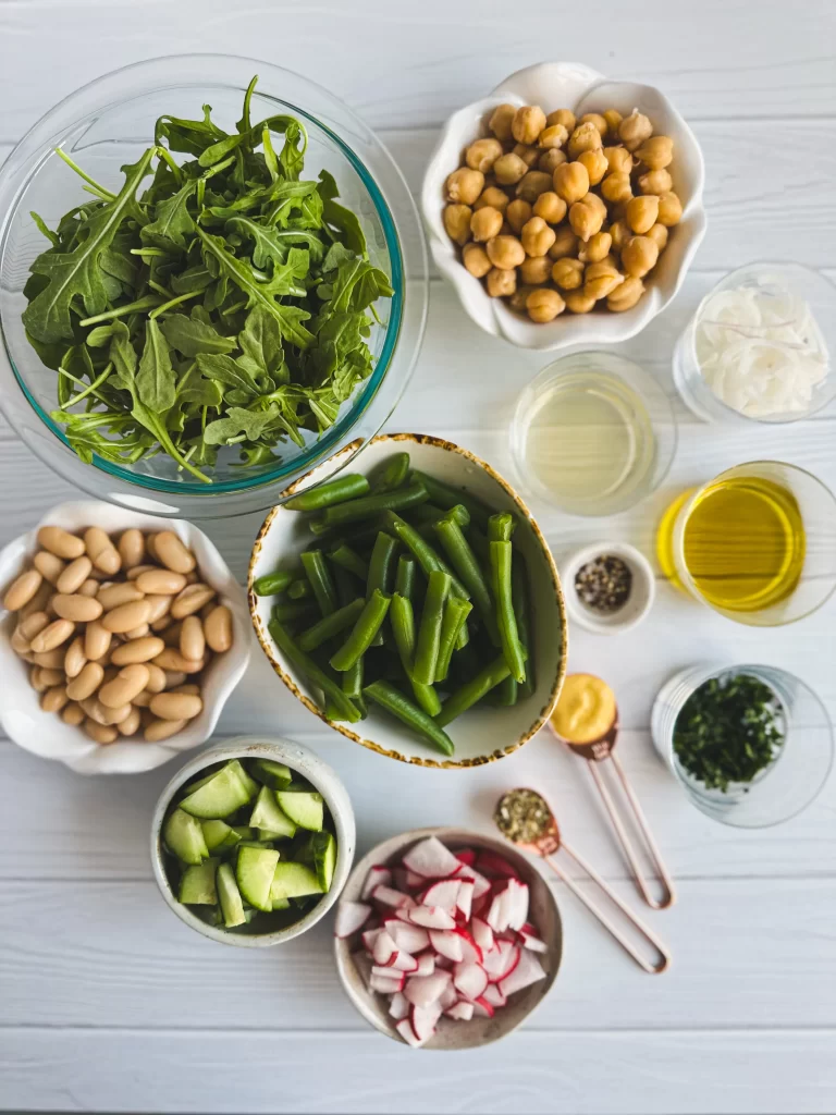 Ingredients needed to make three bean salads on a wood table displayed in circle