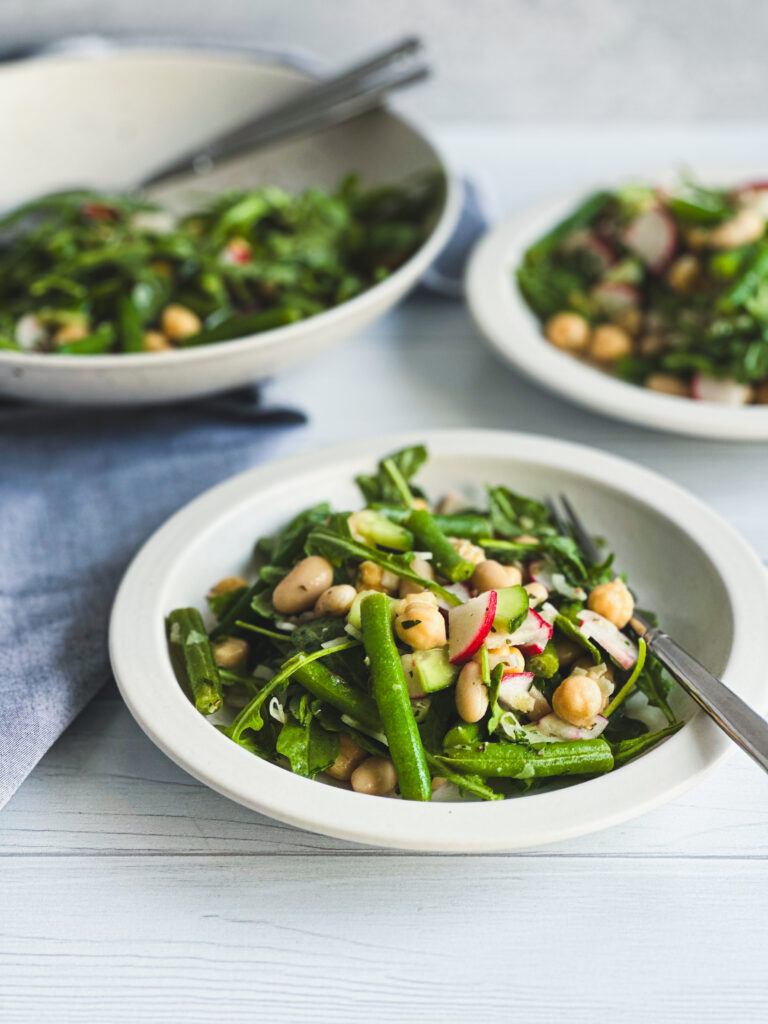 Three bean salad in 2 plates with a bowl in back ground