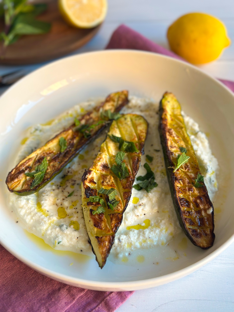 Roasted zucchini over whipped ricotta in a white plate