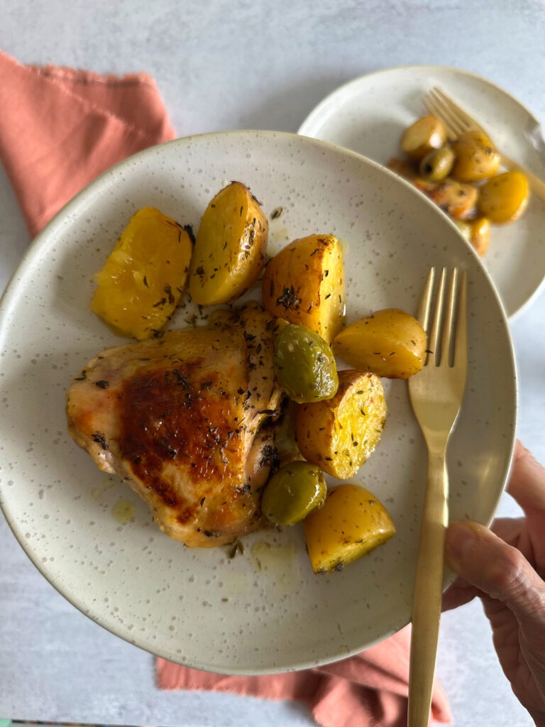 Italian baked chicken and potatoes in one plate in hand