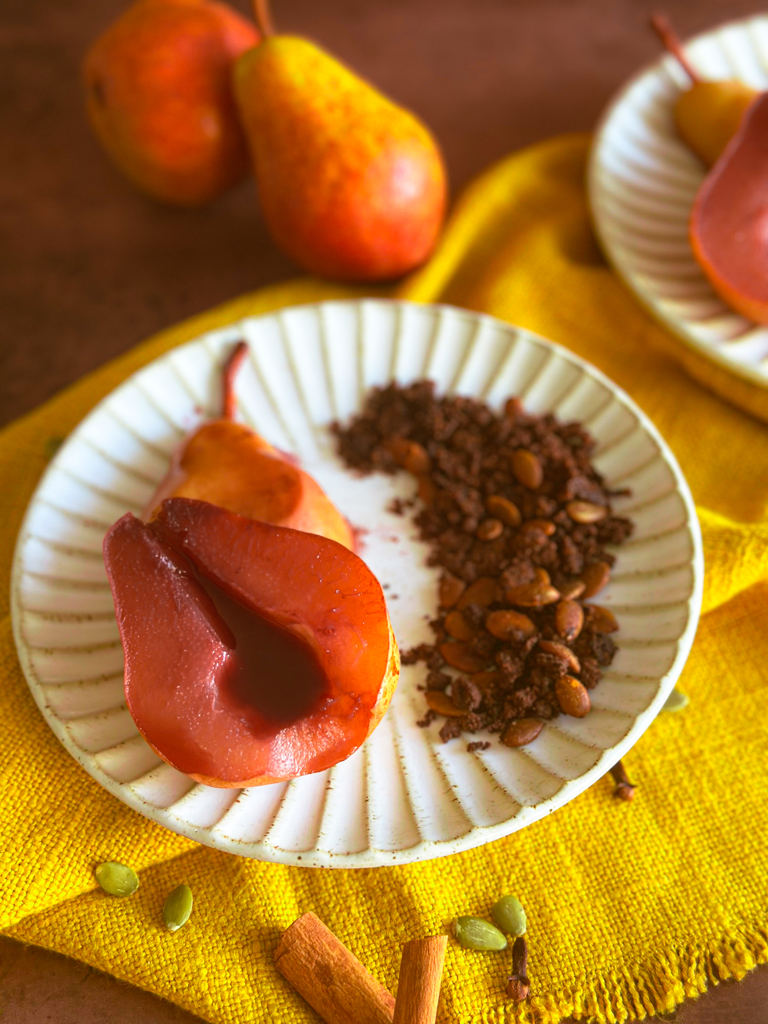 Red Wine Poached pears over a yellow towel on a white rimmed plate