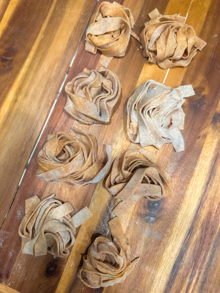 Spelt tagliatelle nests on a wooden board
