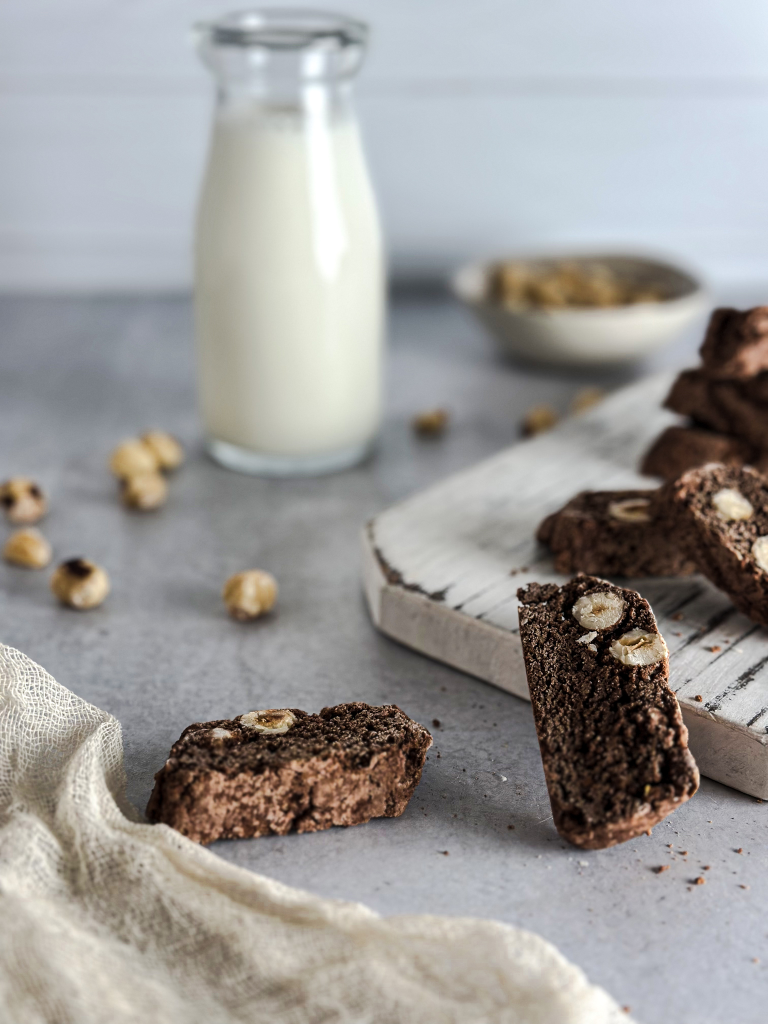 Italian Cocoa and Hazelnut Biscotti on a white tray with a bottle of milk in background.