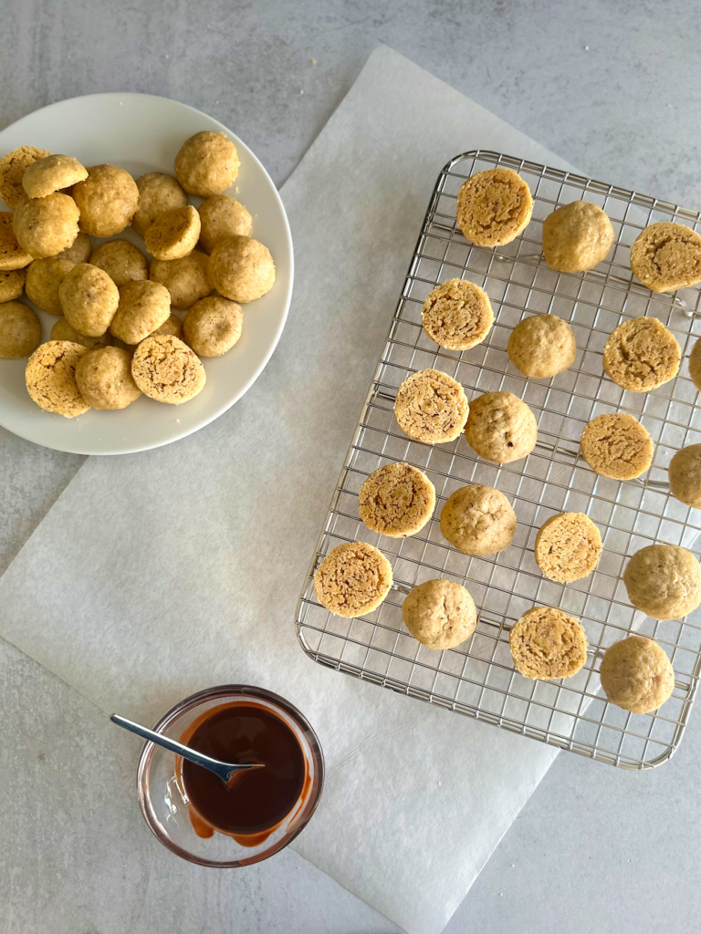 Filling station: cookies on a baking grid, melted chocolate and additional cookies to assemble