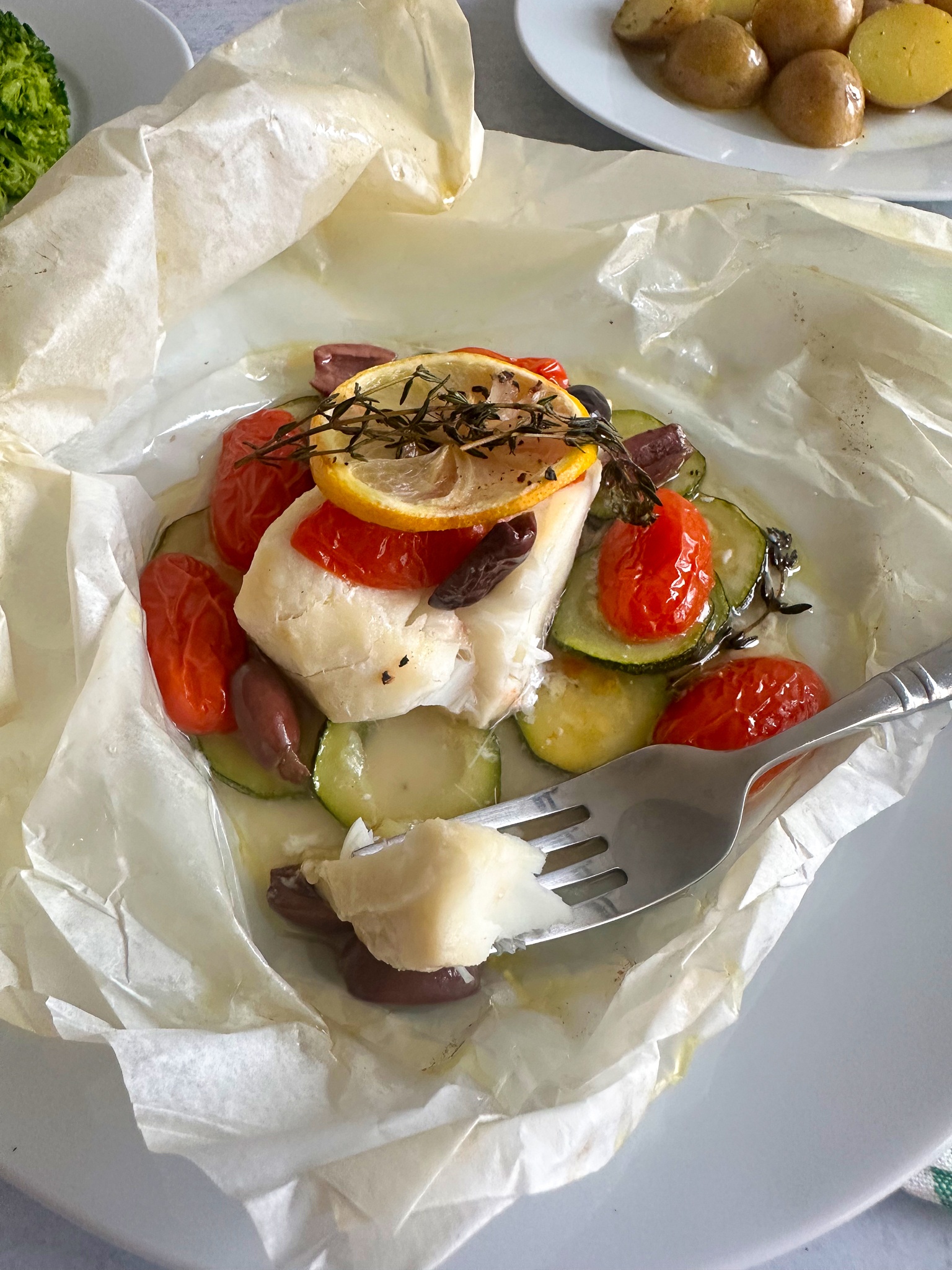 fork with a bite of cod cooked in parchmeent paper.
