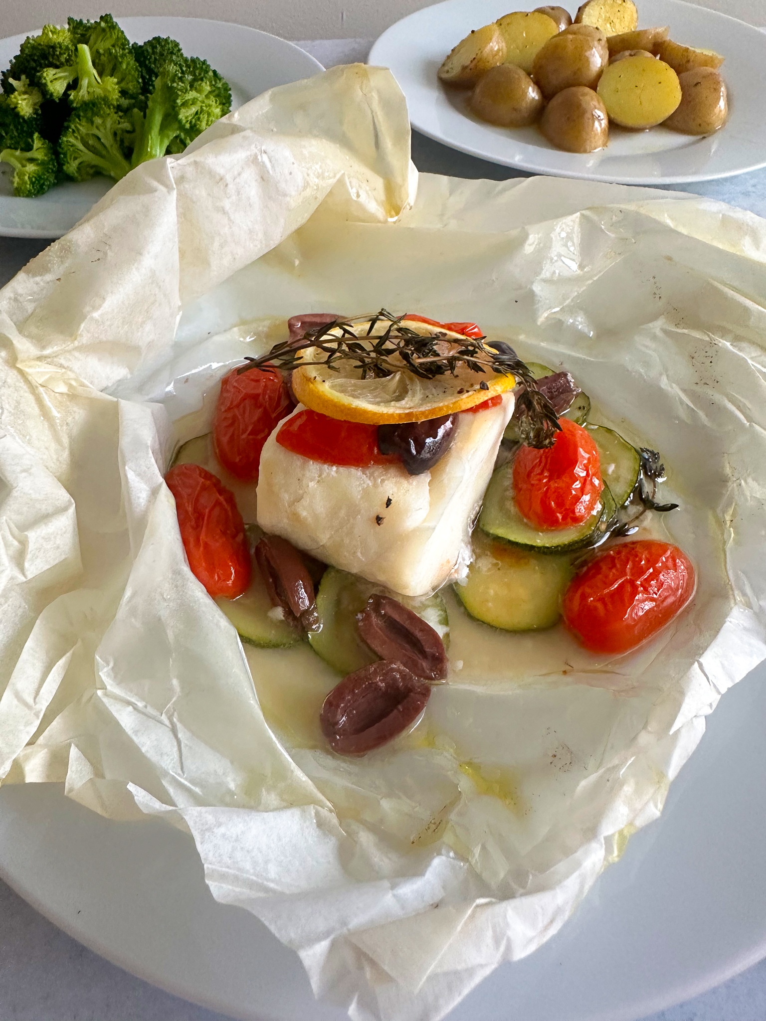 Flaky cod en papillote with zucchini, cherry tomatoes, and black olives