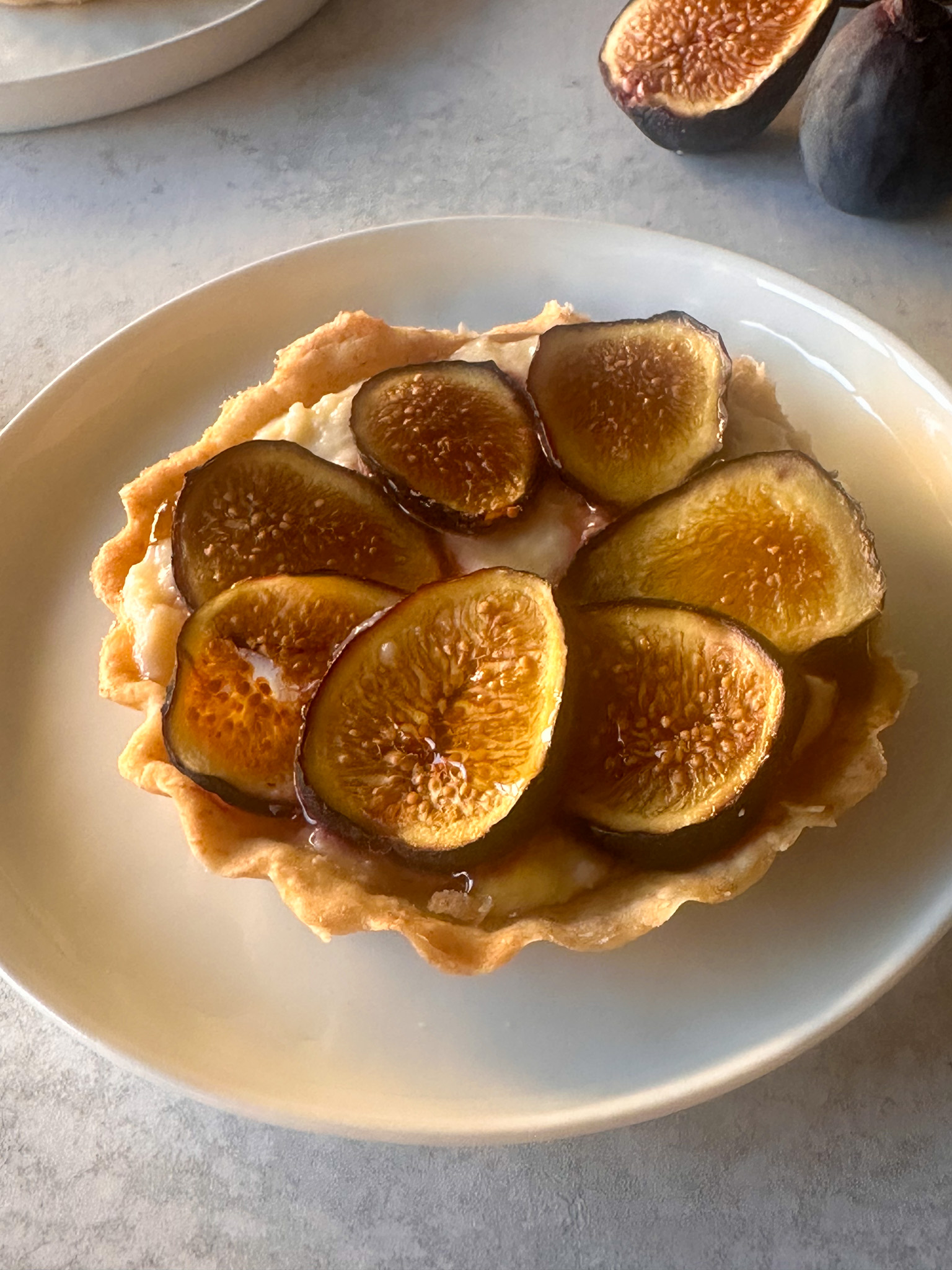 Fresh-Fig-tartlets-with-Ricotta-and-Honey_on a white plate with figs in background